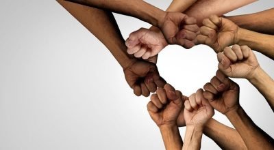 Team of diverse racial backgrounds forming a heart with their hands and arms to symbolize an empathetic work culture
