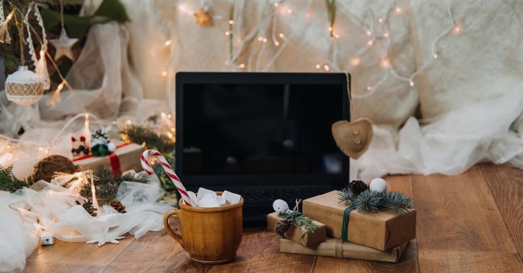 Festively-decorated-living-room-with-a-laptop-in-front-of-the-Christmas-tree-hot-cocoa-and-presents-to-symbolize-a-remote-Christmas-party